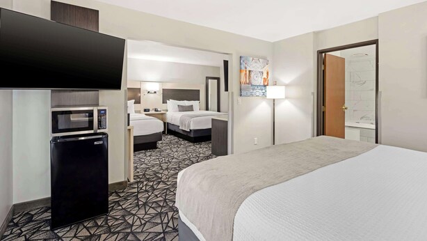 A hotel room with a bed, a flat-screen TV, a microwave, a refrigerator, and a bathroom visible through an open door. - Best Western Morton Inn (Morton)