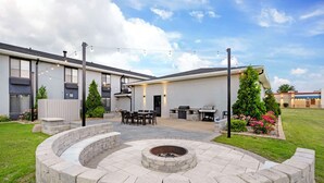 A modern outdoor patio with a circular stone fire pit, a dining area, and a barbecue grill. - Best Western Morton Inn (Morton)