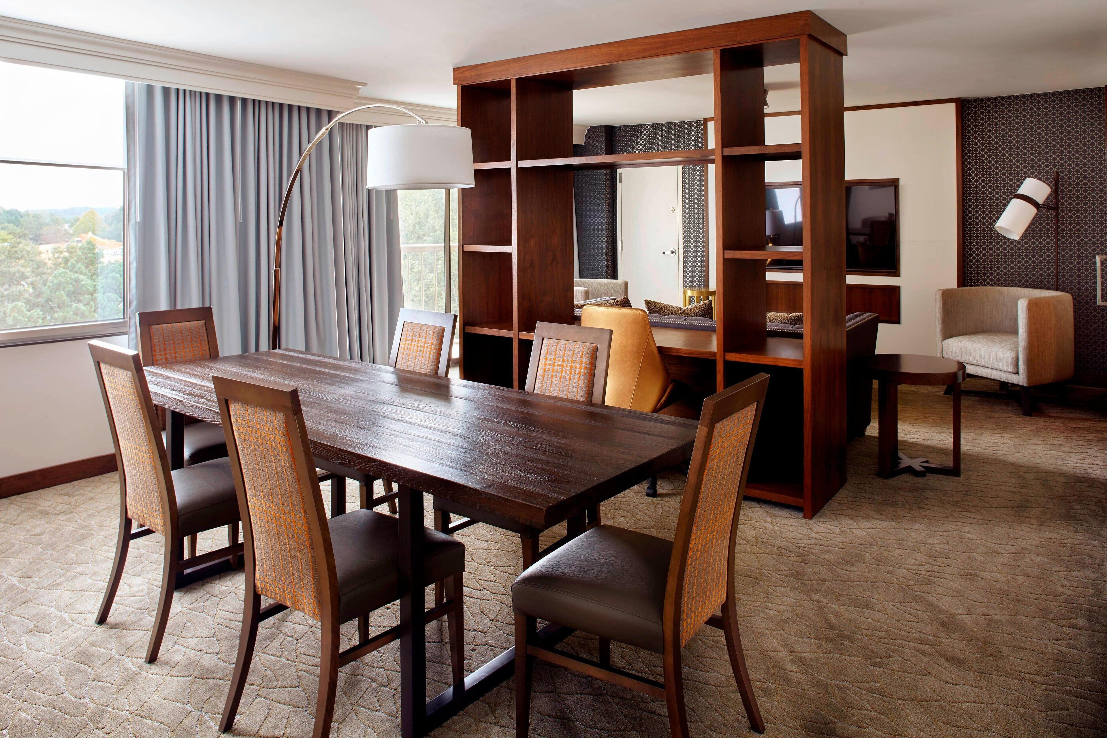 A dining area with a wooden table and chairs, a large bookshelf, and a television.