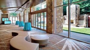 A spacious lobby with a patterned carpet, a curved seating area, and a stone fireplace.