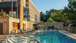 A swimming pool with sun loungers and a stone wall.