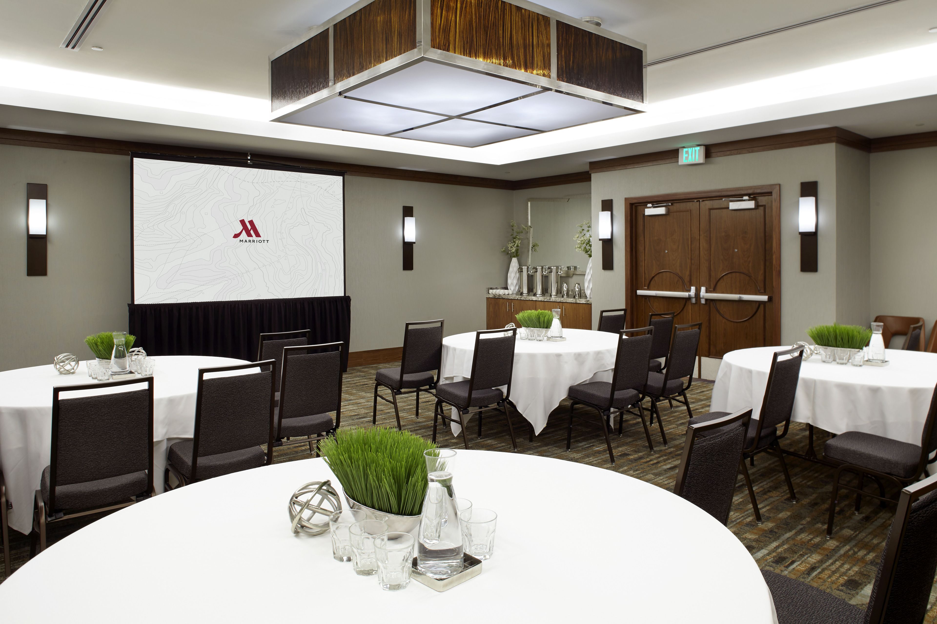 A conference room with multiple round tables, each set with chairs and centerpieces.