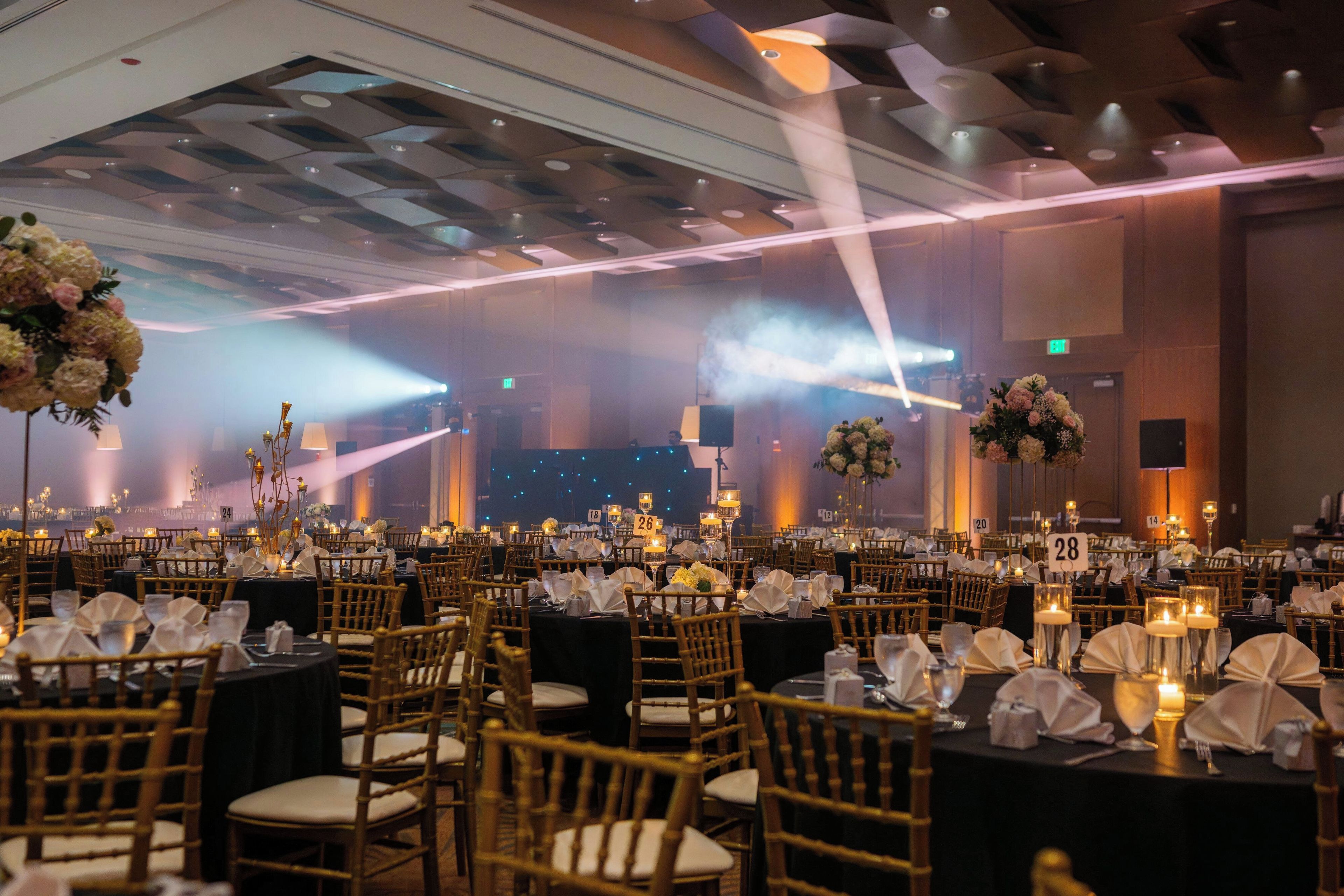 Une salle de banquet avec des tables dressées pour des événements, des chaises et des centres de table floraux.