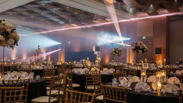Une salle de banquet avec des tables dressées pour des événements, des chaises et des centres de table floraux.