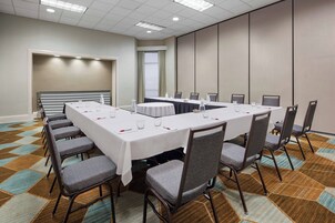 Un salón de conferencias con una larga mesa, sillas y una pantalla para proyector.