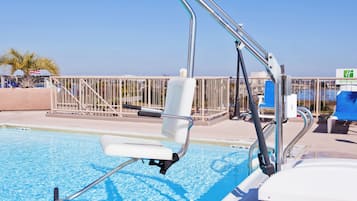 A pool area with a lifeguard chair, poolside chairs, and a railing.