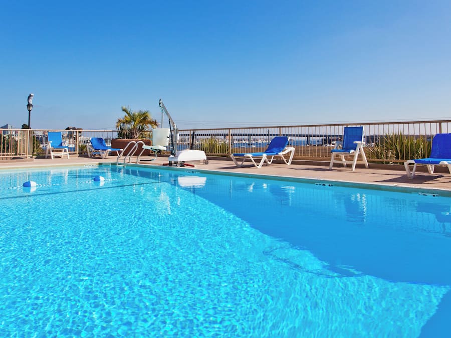 Piscina azul límpida com espreguiçadeiras e posto de salva-vidas.