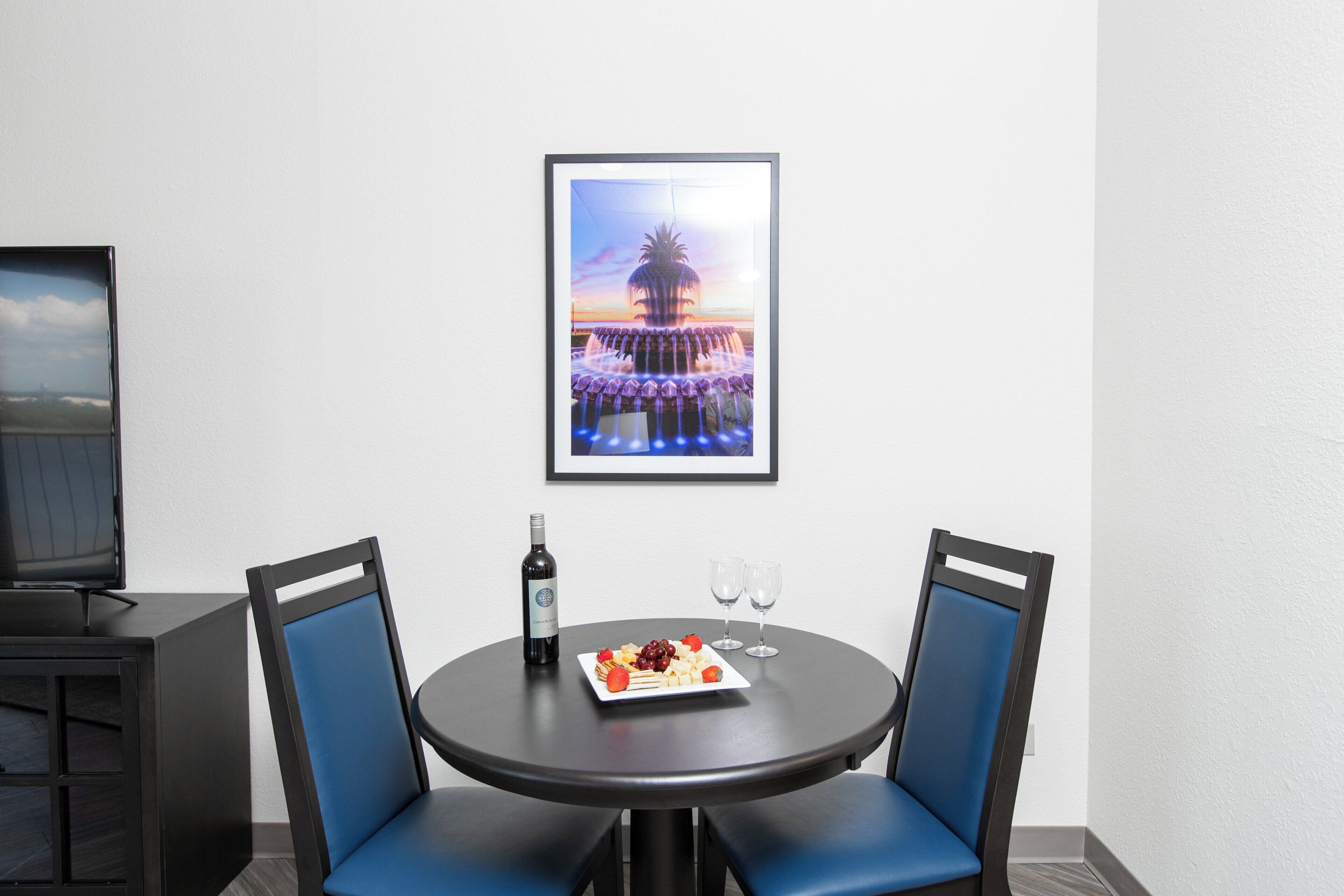 Un coin repas avec deux chaises, une table, une bouteille de vin et une assiette de nourriture.