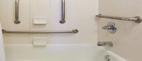 A bathroom with a bathtub, grab bars, and a soap dish.
