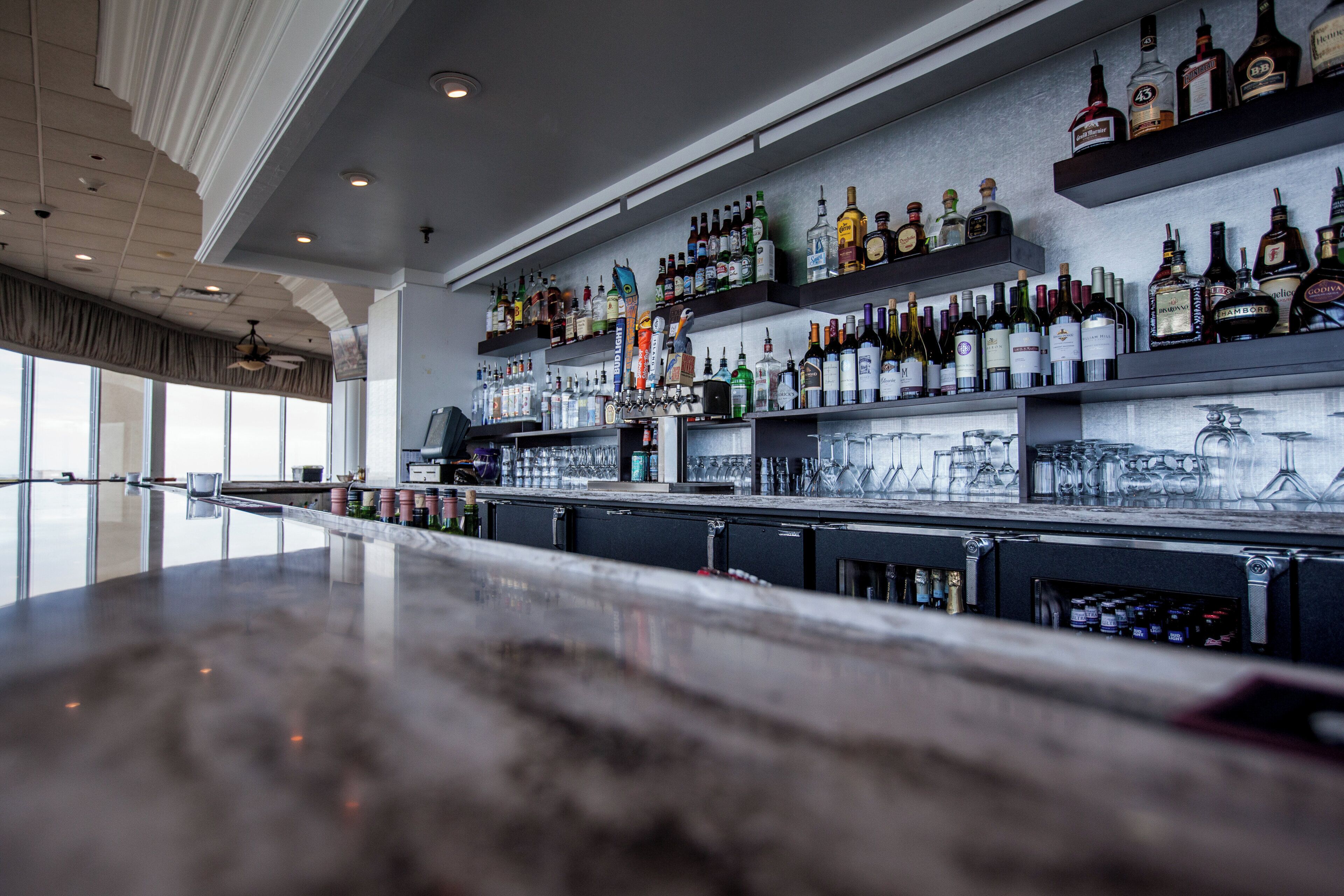 A bar area with shelves stocked with various liquor bottles and glasses.
