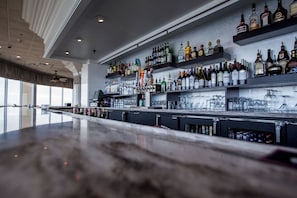 A bar area with shelves stocked with various liquor bottles and glasses. - Holiday Inn Charleston Riverview by IHG (Charleston)