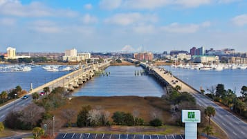 A Holiday Inn sign, a marina with boats, a bridge, and a city skyline in the background.