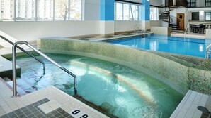 An indoor swimming pool with clear water, a tiled edge, and a staircase leading into the pool.