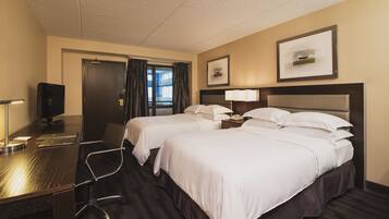 Une chambre d’hôtel avec deux lits, un bureau avec un ordinateur, un téléphone et une télévision.