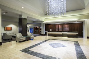 Eine geräumige Lobby mit einer Rezeption, einer Sitzecke und einer modernen Deckenleuchte.