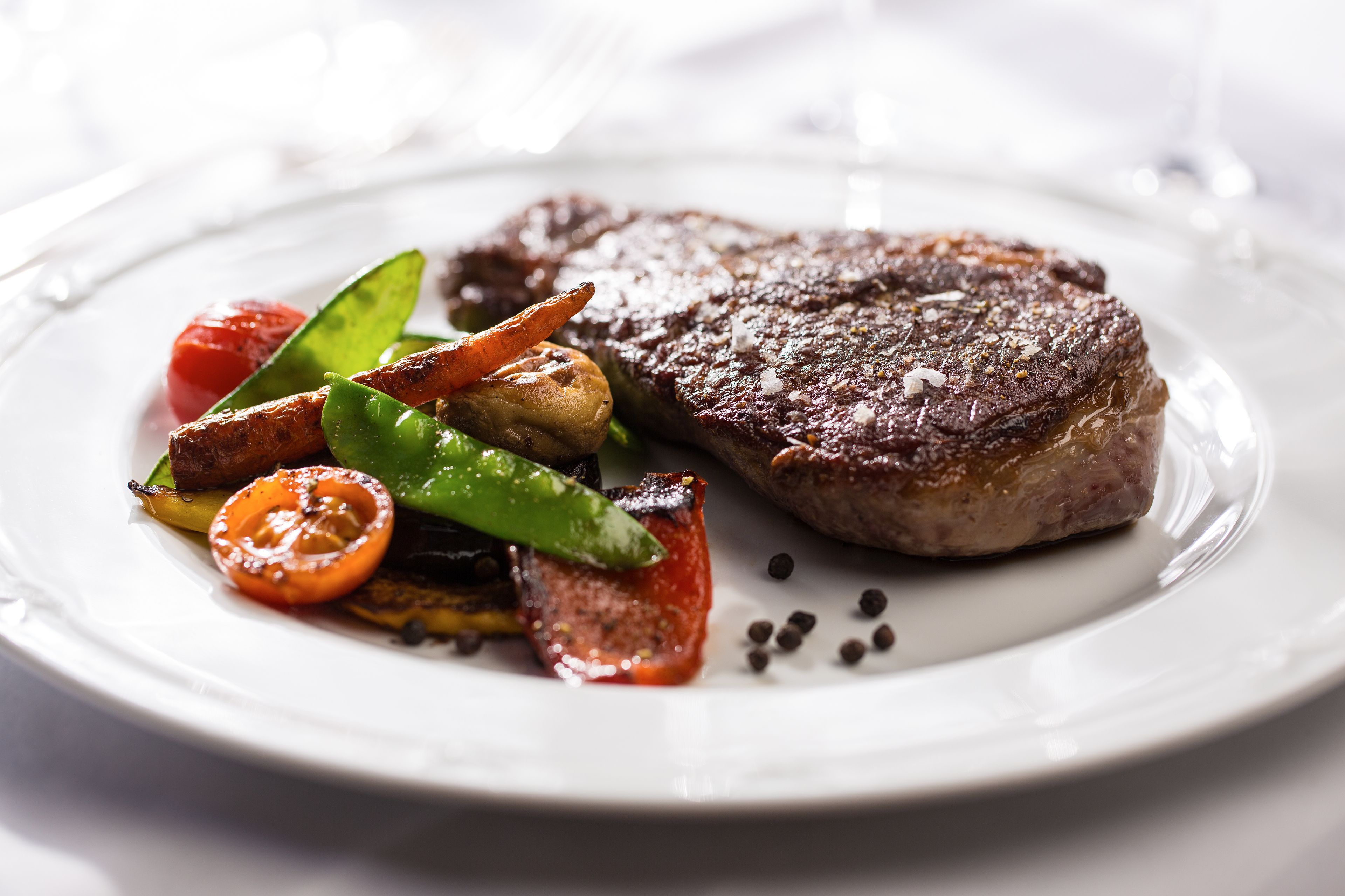 A steak with vegetables on a white plate.