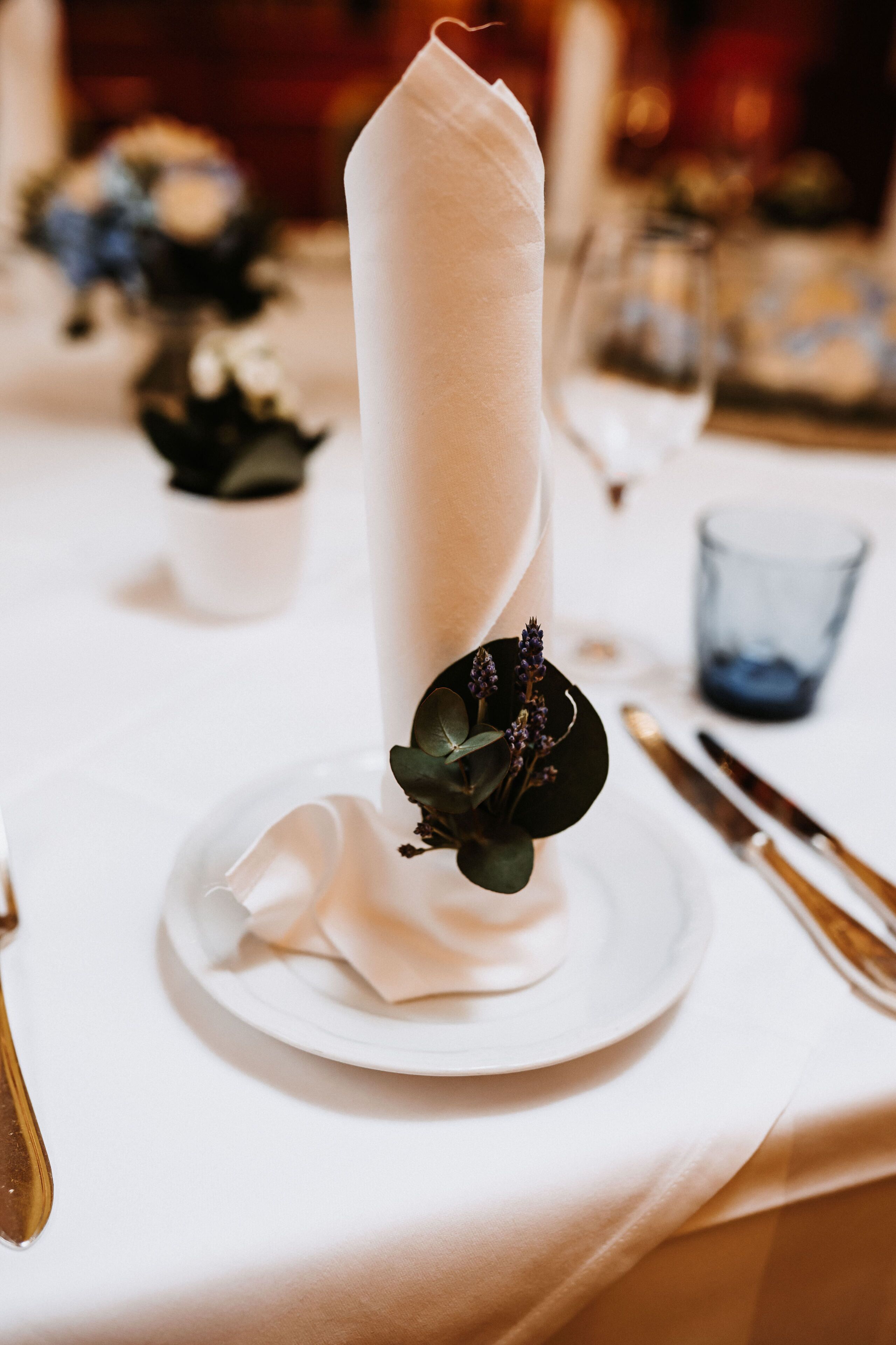 Una mesa dispuesta con servilleta blanca, un pequeño arreglo floral y un vaso de agua.
