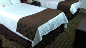 A hotel room with two beds, a nightstand with a lamp, and a small desk. - Nation's Inn Kinston (Kinston)