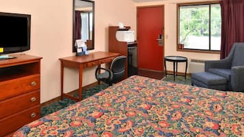 Habitación de hotel con una cama grande, un escritorio con silla, televisor, microondas y ventana con cortinas.