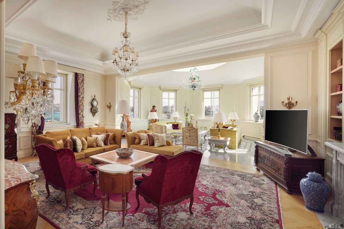 A spacious living room with a large sofa, matching chairs, a coffee table, and a television.