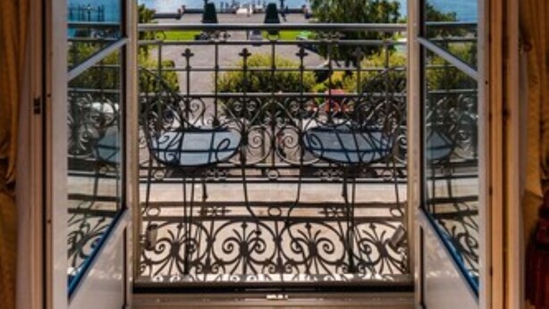 A balcony with a view of a lake and a fountain.
