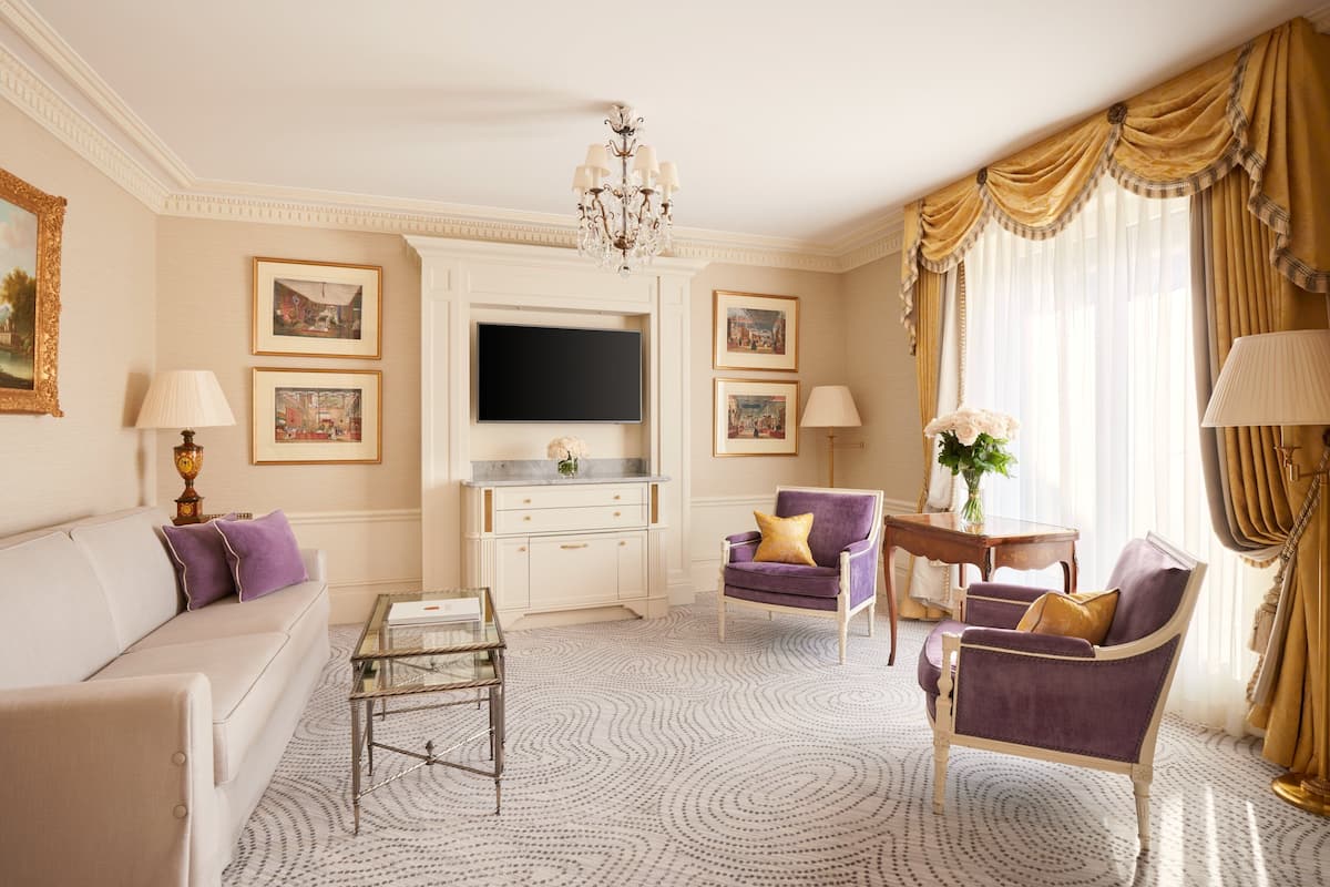 A well-appointed living room with a sofa, armchairs, a coffee table, a TV, and a decorative chandelier.