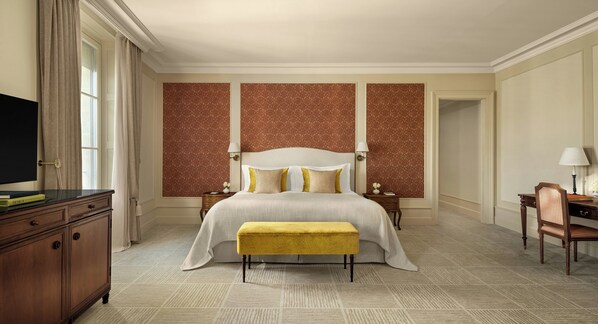 A hotel room with a large bed, a desk, a chair, and a television.