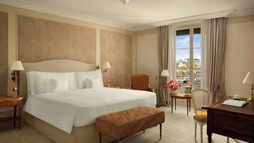 A hotel room with a large bed, a wooden bench, a desk, and a chair.