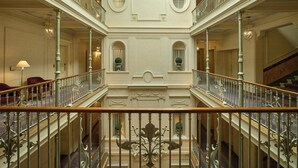 A grand interior with a central atrium, ornate railings, and a staircase leading to an upper level. - Beau Rivage Geneva (Geneva)