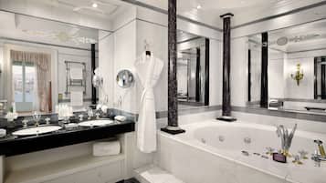 A luxurious bathroom with two sinks, a large bathtub, and a mirror with a decorative frame.