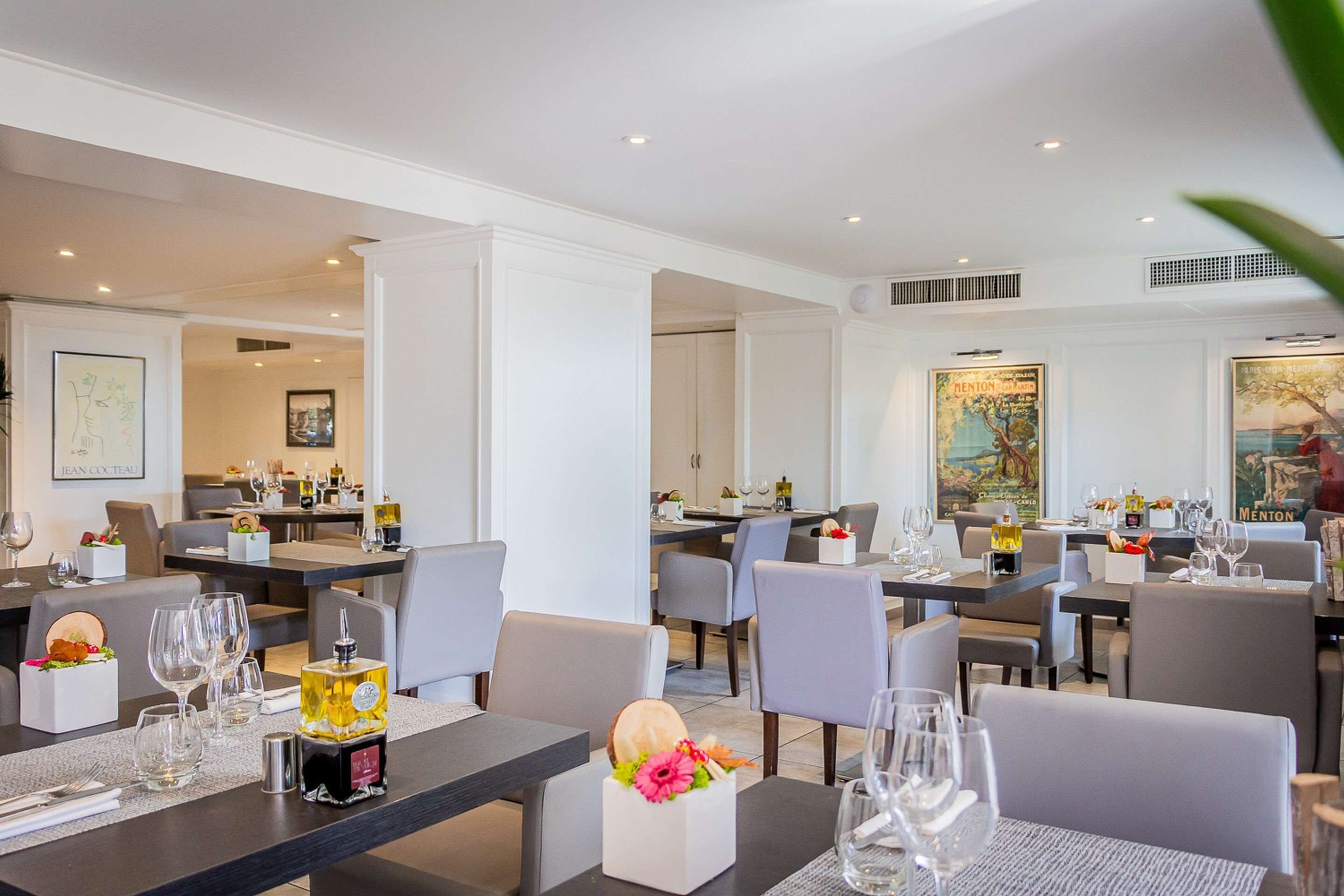 Un espace de restauration moderne, doté de plusieurs tables et chaises, et proposant une variété d’accessoires de table, notamment des verres et des bouteilles de vin.