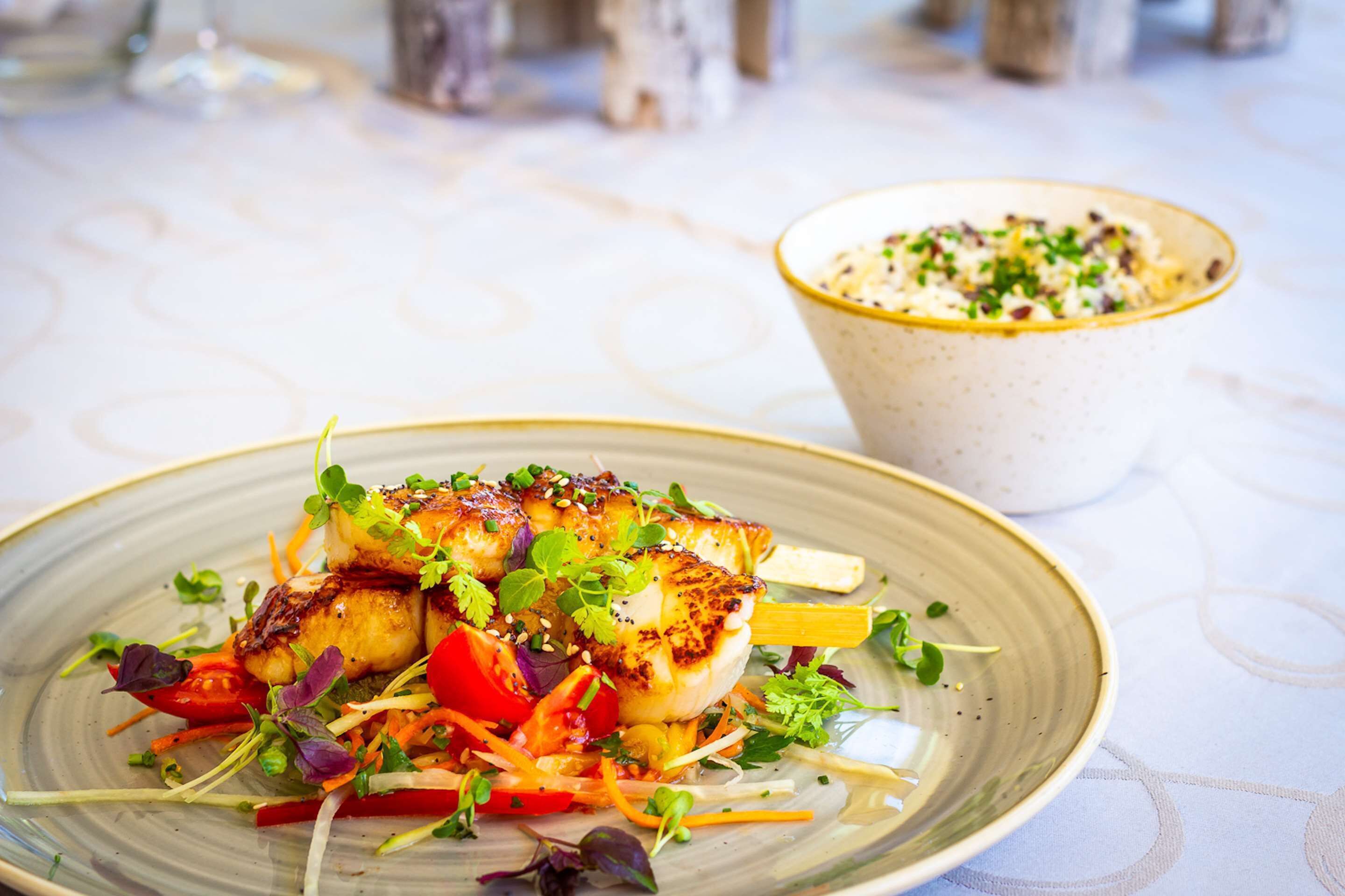A plate of grilled fish with vegetables and a bowl of soup.