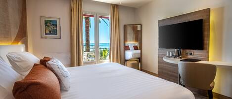 A hotel room with a large bed, a desk, a flat-screen TV, and a balcony with a view.