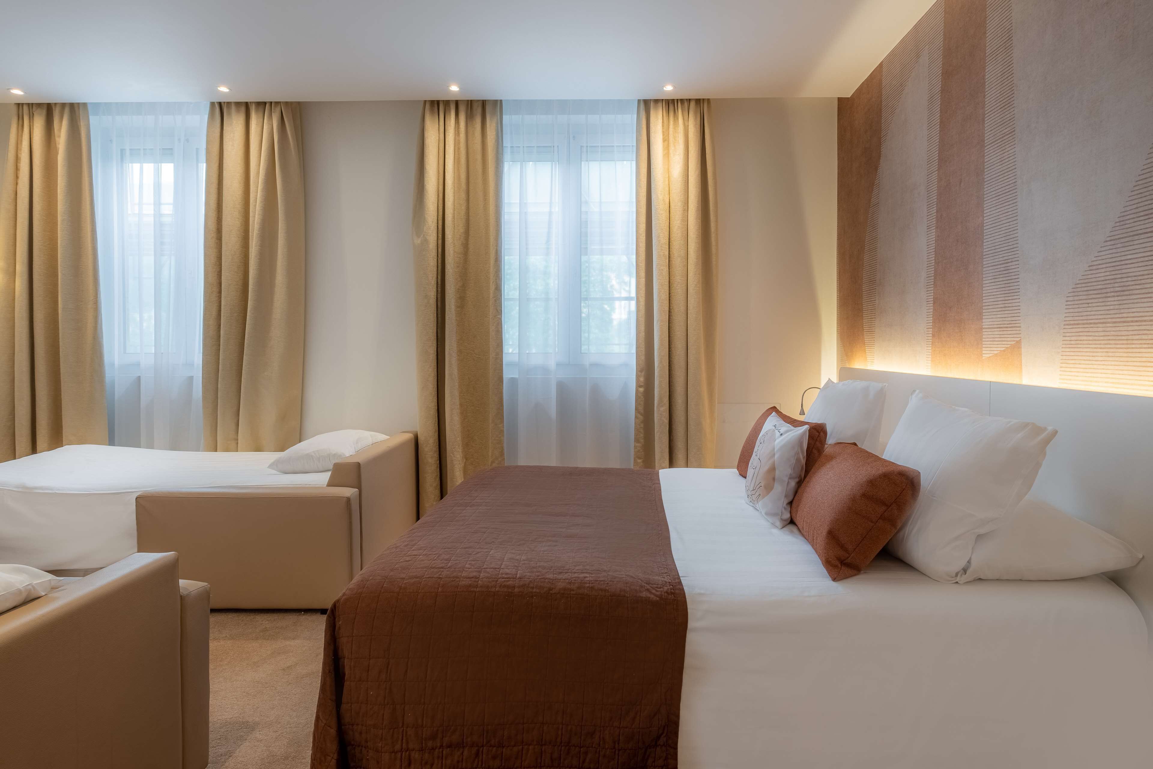 A hotel room with a large bed, two armchairs, and a sofa.