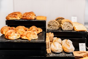 Mostrador de panadería con diversas opciones de productos horneados, incluyendo croissants, panecillos y pastelería.