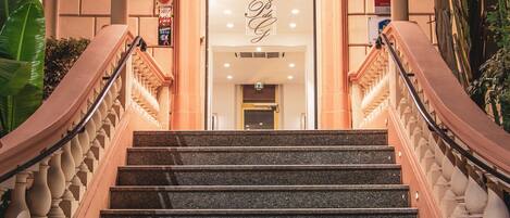 A grand staircase leading to a lobby with a stone wall and a large arched entrance.
