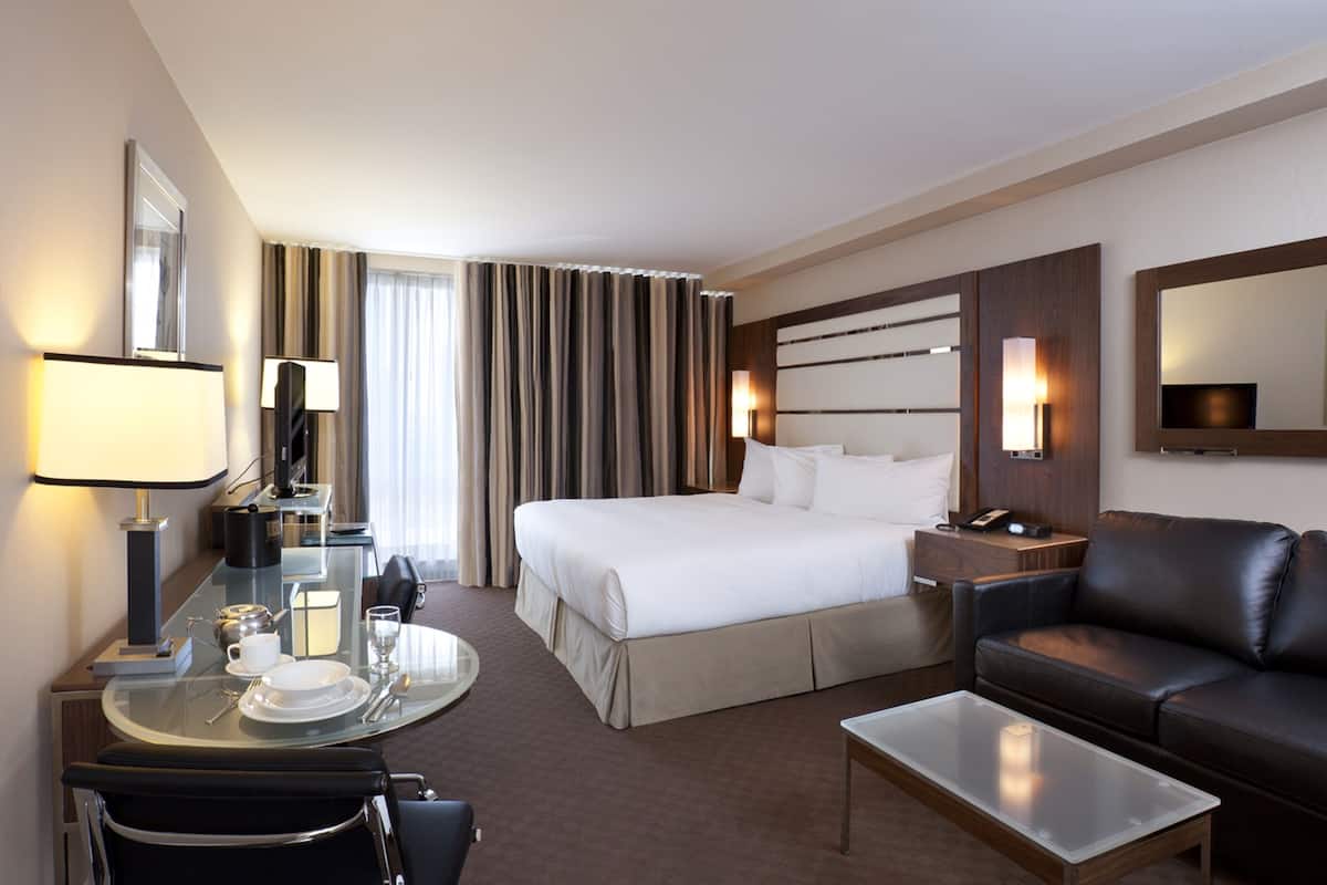 Une chambre d’hôtel comprenant un lit, un bureau avec une chaise, une table basse, un canapé et un téléviseur.