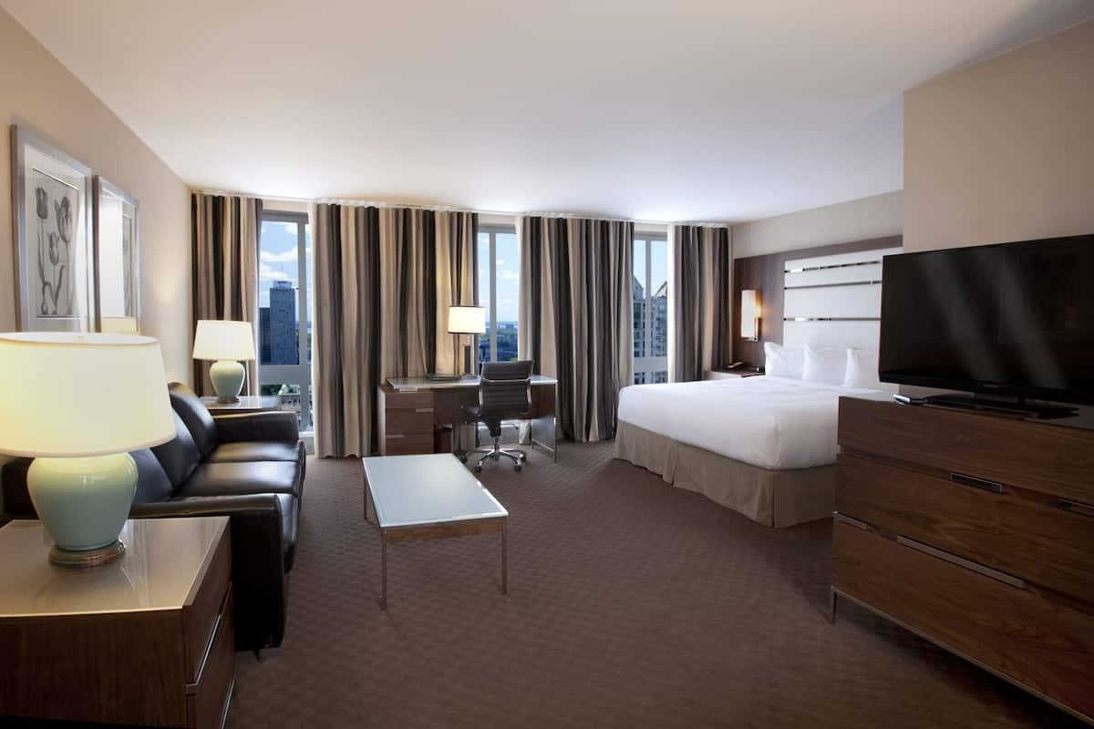 Une chambre d’hôtel équipée d’un lit, d’un bureau, d’une chaise, d’une télévision et offrant une vue sur la ville.