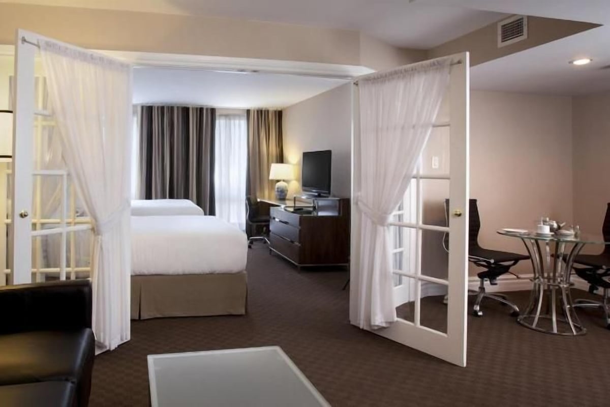 Una habitación de hotel con cama, escritorio, televisión, silla y una pequeña mesa.