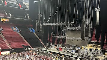 Un estadio interior grande con varios niveles de asientos, un escenario y diverso equipamiento técnico.