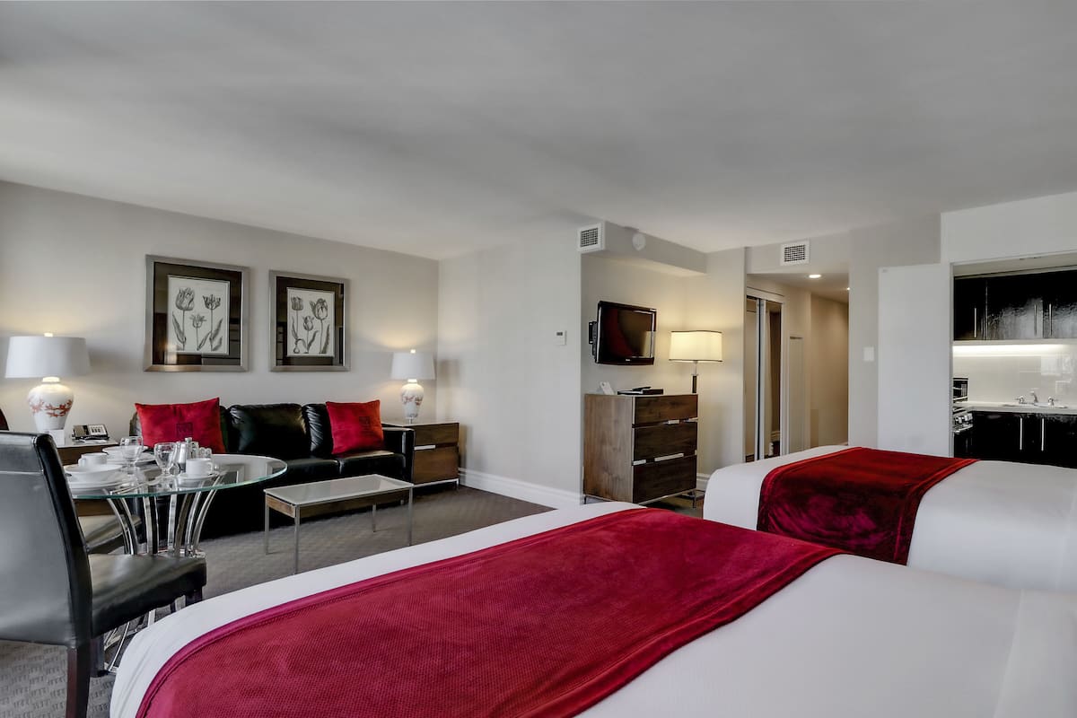 Une chambre d’hôtel avec deux lits, un coin repas, une télévision et une salle de bain.