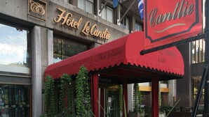 Hotel Le Carlton con un toldo rojo, banderas estadounidenses y un letrero.