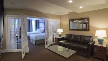 A hotel room with a bed, a leather sofa, a coffee table, two bedside tables with lamps, and a mirror on the wall.
