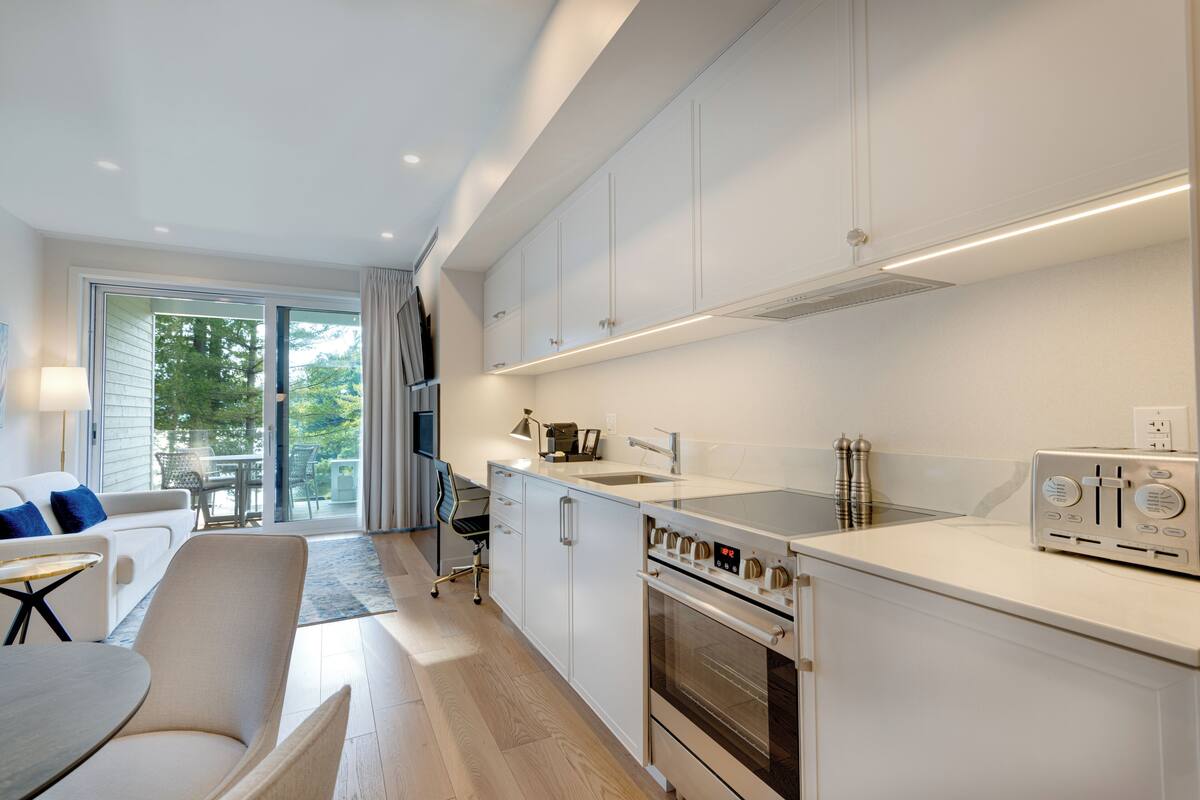 A modern kitchen with white cabinetry, a built-in oven, and a toaster.
