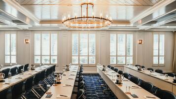 A conference room with long tables, chairs, and a chandelier.