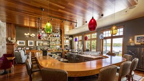 A bar area with a wooden bar counter, multiple seating options, and a variety of bottles and glasses.