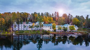 A lakeside hotel with multiple buildings, a dock, and a reflection in the water.