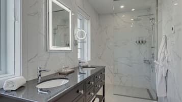 A modern bathroom with two sinks, a large mirror, and a glass-enclosed shower.