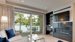 A modern living room with a sofa, a glass coffee table, and a TV mounted on the wall.