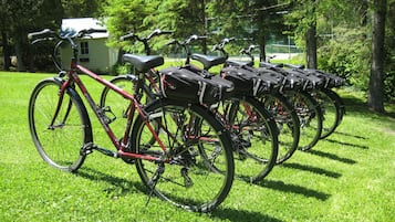 Bicycles parked on a grassy area with trees in the background.